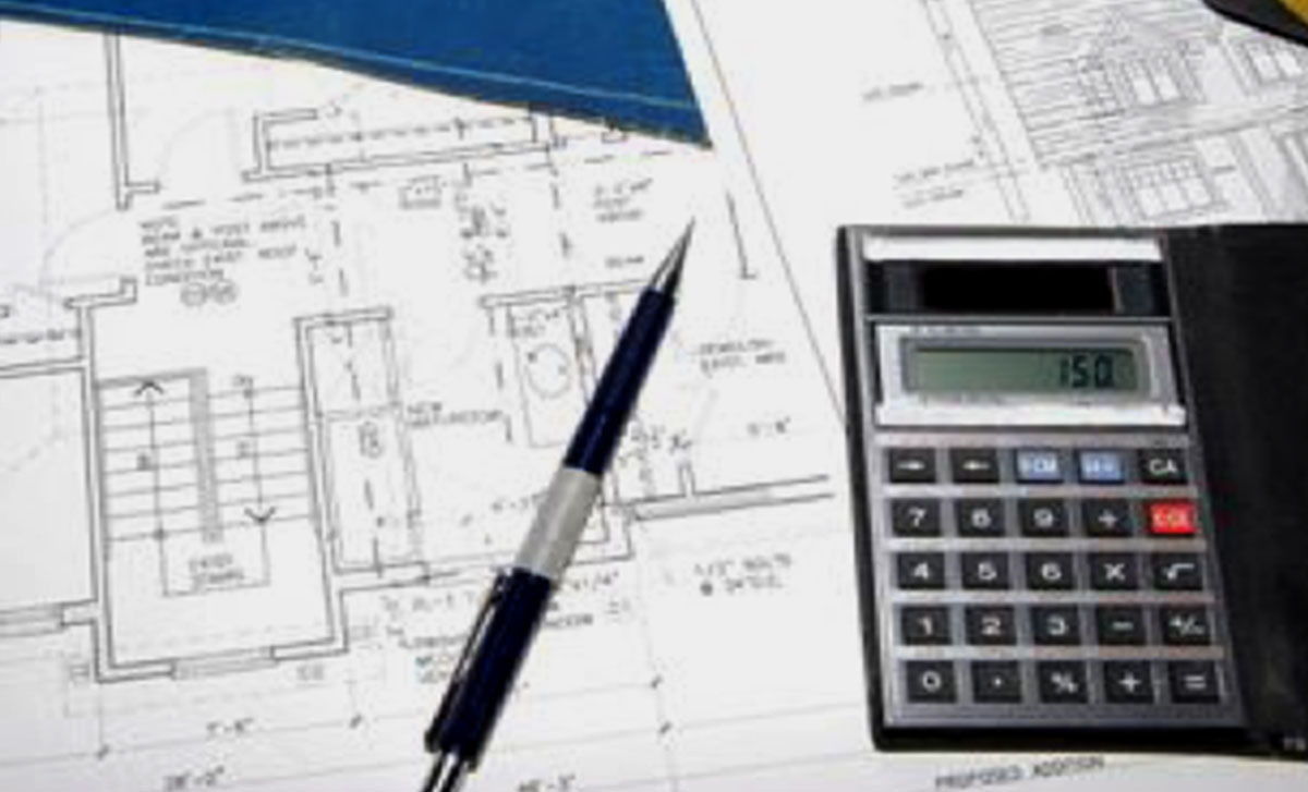 Calculator and pen lay on top of kitchen design plans